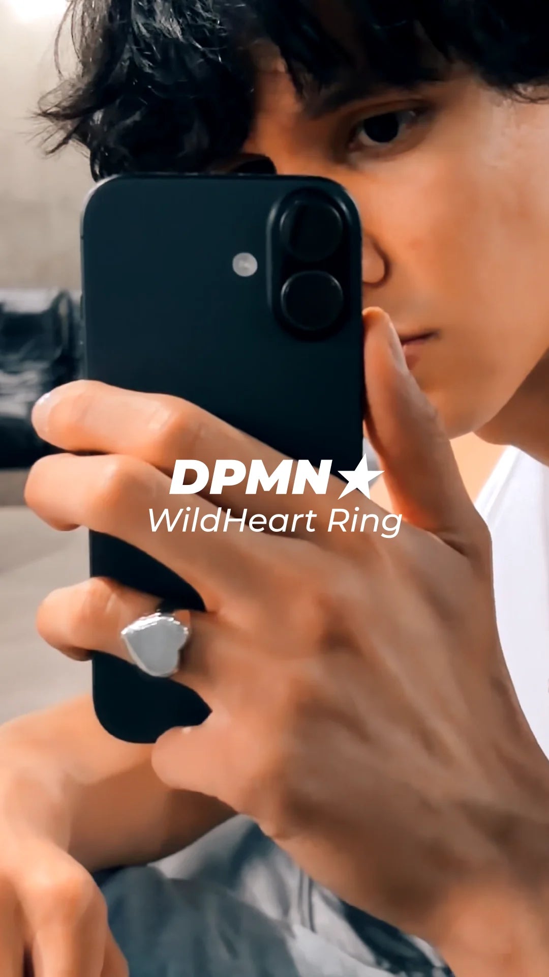 Lanzamiento Anillo Wildheart DPMN★ — anillo de plata .950 con sello de corazón, visto en la mano sosteniendo un teléfono